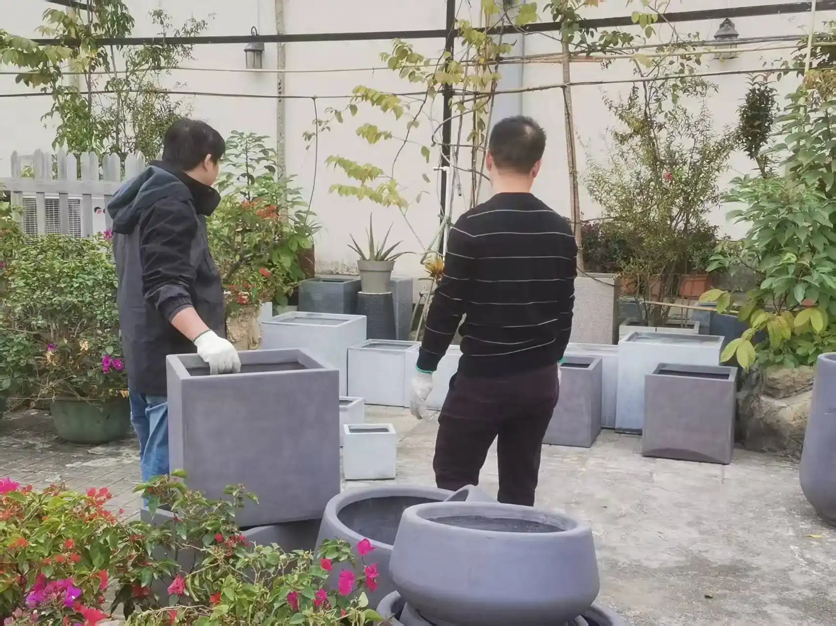 Two Ronglin staff members moving grey GRC planters into the rooftop garden